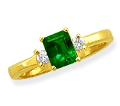 Clean-lined Ring is prong-set with a fine Emerald-cut Emerald center gem accompanied on either side by a fine matched Diamond