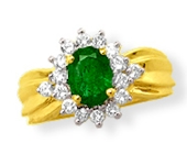 Ring carries its rich oval-cut fine Emerald in a garland of brilliant white round-cut Diamonds 